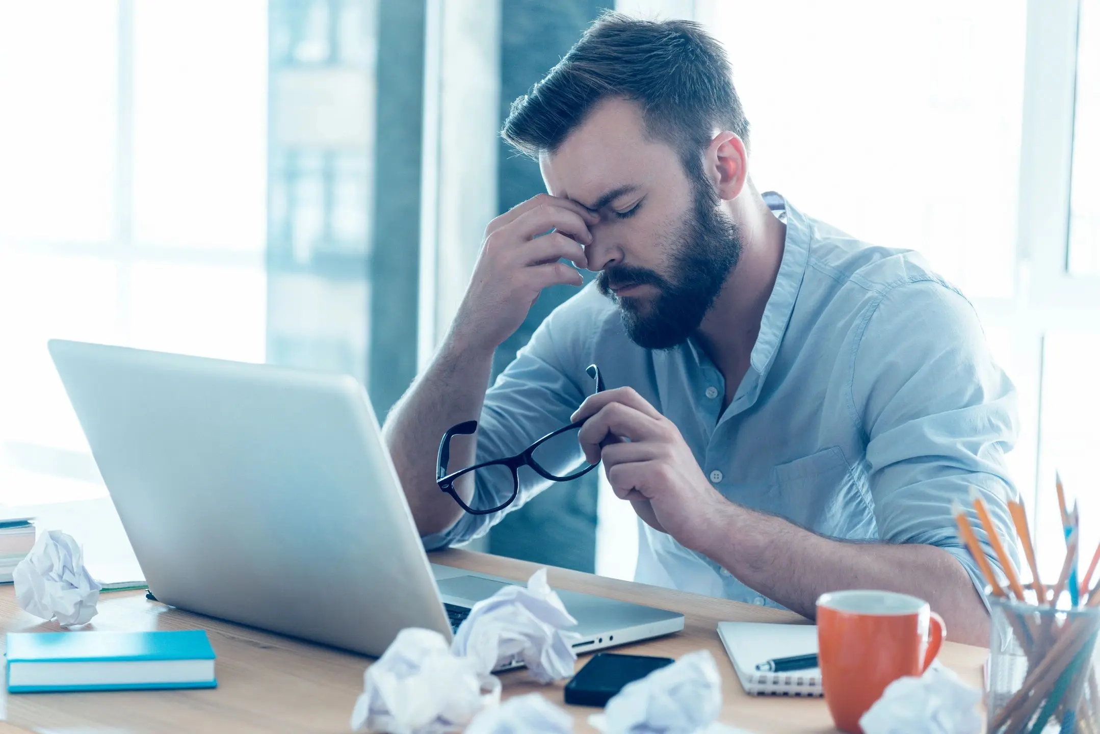 Male office worker suffering a mental crisis at his desk